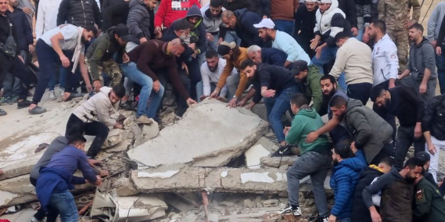 dpatopbilder - Rettungskräfte und Anwohner suchen nach Überlebenden in den Trümmern eines eingestürzten Gebäudes. Foto: Uncredited/AP/dpa