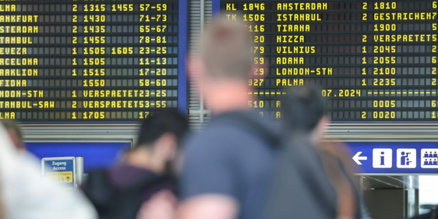 ARCHIV - Reisende warten vor der Anzeigentafel am Nürnberger Flughafen, die verspätete oder gestrichene Flüge anzeigt. Weltweite Probleme in den Computersystemen störten damals auch...