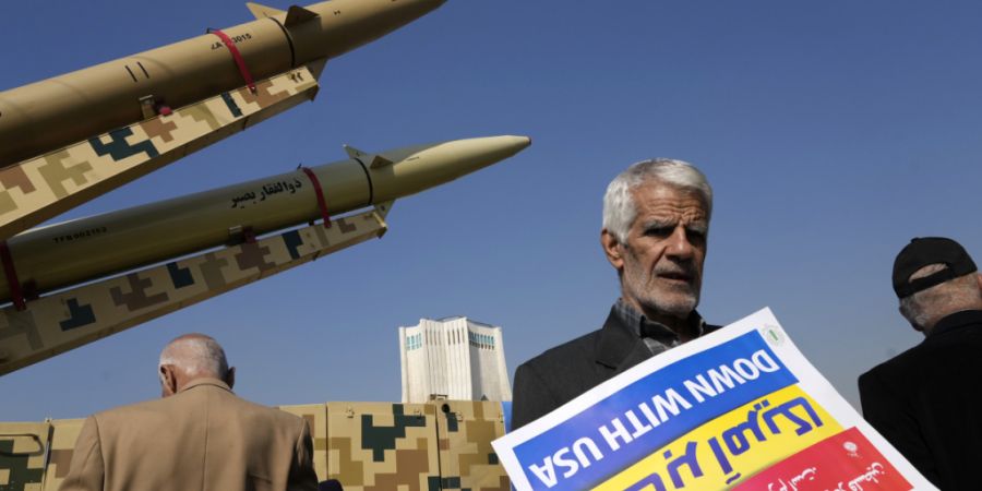 ARCHIV - Ein Mann hält ein Anti-US-Plakat auf dem Kopf vor den iranischen Raketen, die auf der jährlichen Kundgebung zum Gedenken an die Islamische Revolution von 1979 ausgestellt sin...