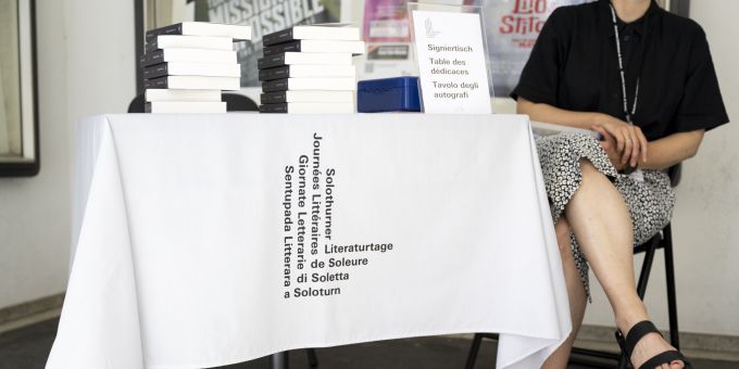 Das Logo des Festivals wird auf der Tischdecke eines Autogrammtisches vor dem Kino Palace fotografiert. Festivals