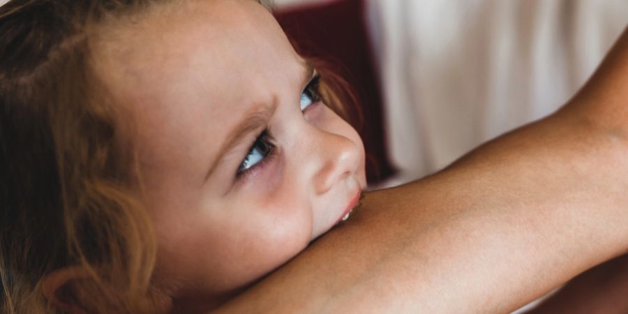Kind beisst Person in den Arm