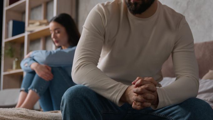 Auch emotionale Untreue kann zum Beziehungsaus führen. Traurige Frau, im Vordergrund sitzt der Partner