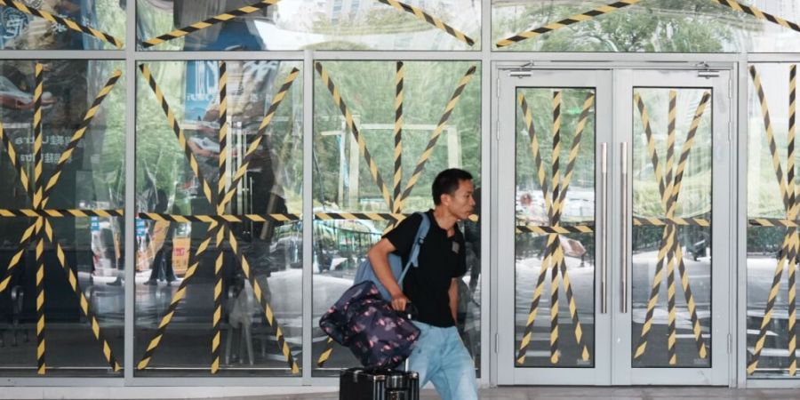 Ein Fahrgast geht an einer verschlossenen Tür eines Busbahnhofs vorbei, an dem alle Glasfenster und -türen zur Vorbereitung auf den herannahenden Taifun «Dolphin» in Hangzhou in der o...