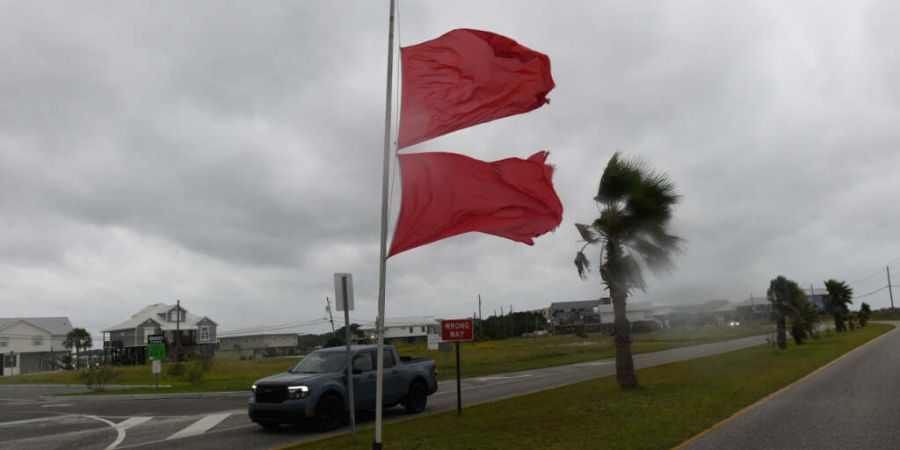 Marineflaggen wehen im Wind, der durch den Sturm «Isaias» verursacht wird, während ein Fahrzeug vorbeifährt. Foto: Octavio Jones/AP/dpa