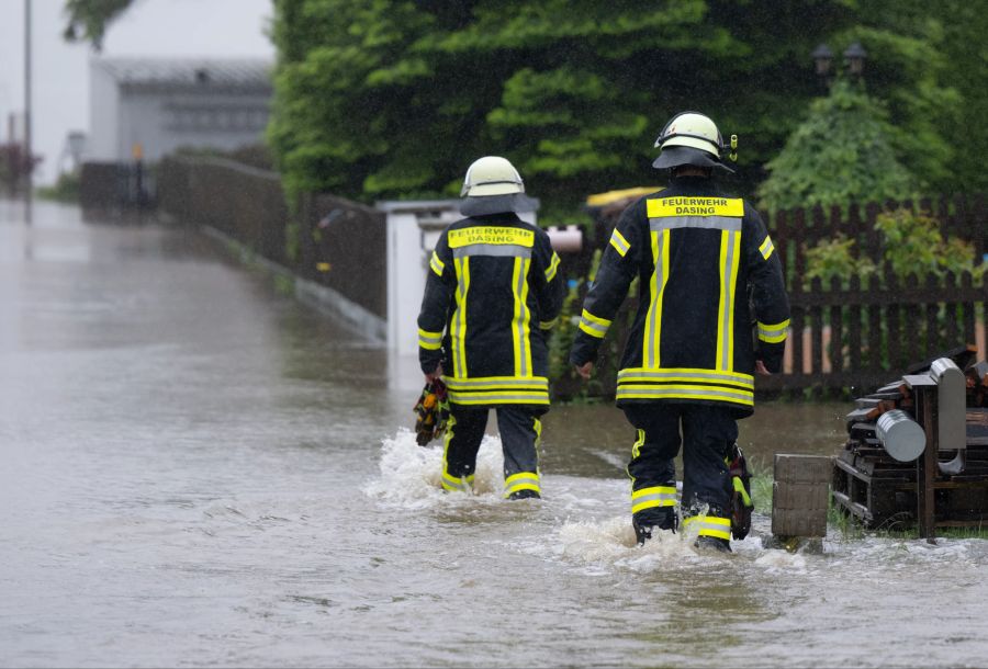 01.06.2024, Bayern, Dasing: Feuerwehrleute gehen über eine überflutet Strasse in Dasing im schwäbischen Landkreis Aichach-Friedberg. Foto: Sven Hoppe/dpa +++ dpa-Bildfunk +++