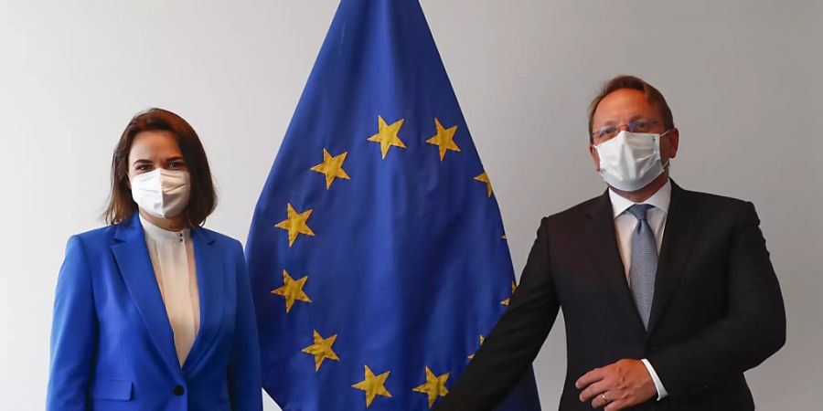 Swetlana Tichanowskaja, Oppositionsführerin aus Belarus, und Oliver Varhelyi, Erweiterungskommissar der EU, stehen zusammen vor einer Fahne der EU während eines Treffens der Aussenminister der EU im Gebäude des Europäischen Rates. Foto: Johanna Geron/Pool Reuters/AP/dpa