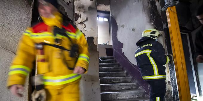 Feuerwehrleute an der Arbeit im vom Brand beschädigten Wohnblock in Genf. Feuerwehrleute an der Arbeit im vom Brand beschädigten Wohnblock in Genf.