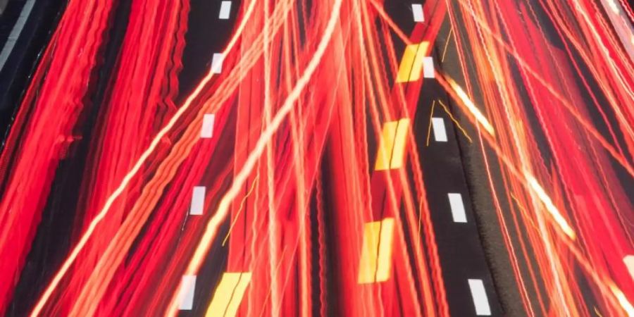 Die Scheinwerfer vorbeifahrender Fahrzeuge ziehen auf einer Autobahn ihre Lichtspuren durch die hereinbrechende Dunkelheit (Aufnahme mit Langzeitbelichtung). Foto: Boris Roessler/dpa