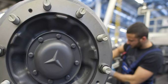 Ein Mitarbeiter ist im Werk von Mercedes Benz hinter der Radaufhängung eines Lastkraftwagens zu sehen. daimler