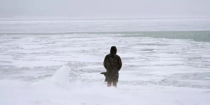 Ein Mann blickt auf den teilweise gefrorenen Michigansee. michigansee