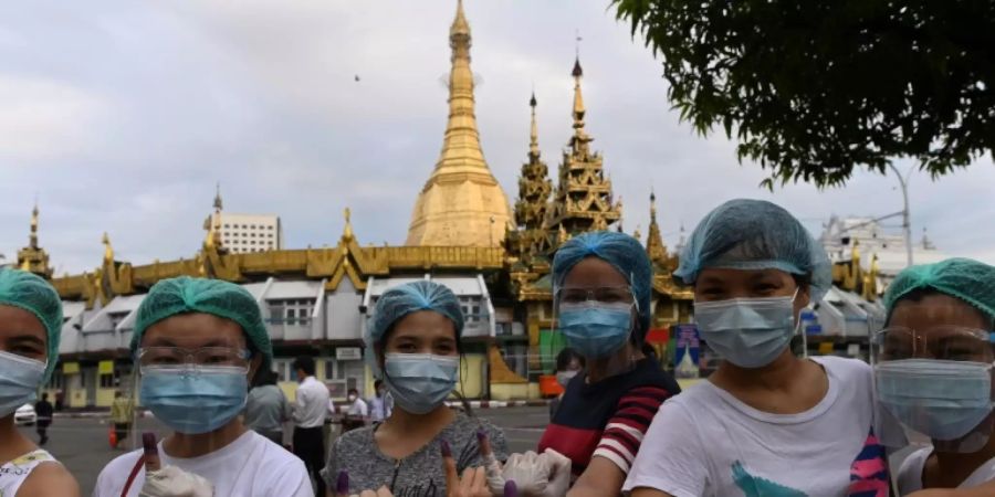 Wählerinnen in Myanmar zeigen ihre tintenblauen Finger