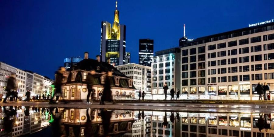 In einer Pfütze spiegeln sich die Hauptwache und die Skyline von Frankfurt. Foto: Boris Roessler/dpa/Archiv