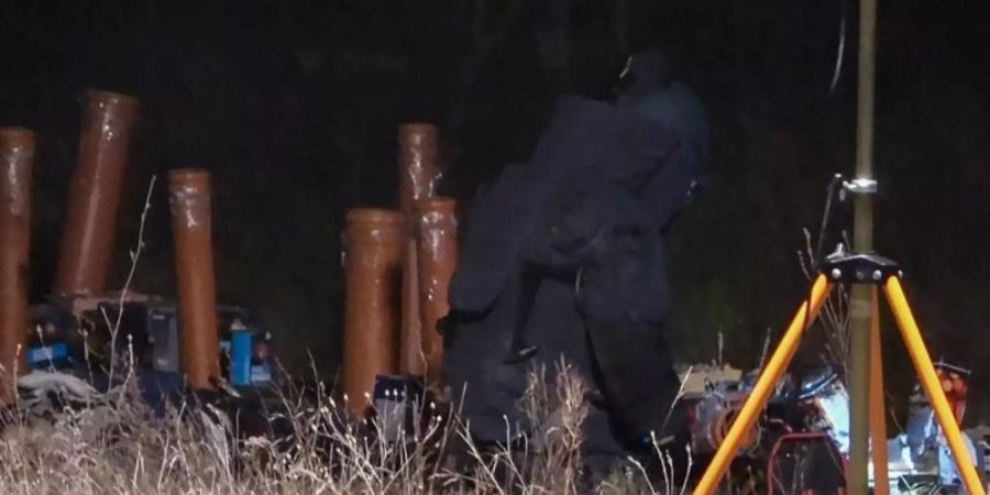 Ein Polizist in Schutzausrüstung untersucht den Unfallort in Rietz-Neuendorf. Foto: Christian Sappeck/BLP/dpa