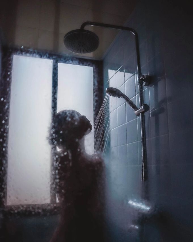 Eine lauwarme Dusche ist bei Hitze besser als eiskaltes Wasser. Frau in Dusche