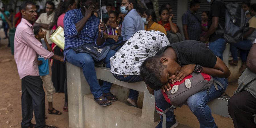 Ein Mann macht ein Nickerchen, während er zusammen mit anderen in einer Schlange vor dem Department of Immigration  Emigration in Colombo, Sri Lanka, wartet, um seinen Pass zu erhalten. Foto: Rafiq Maqbool/AP/dpa