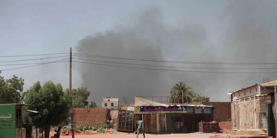 Rauch steigt hinter Gebäuden auf. Viele Menschen sind auf der Flucht vor dem Konflikt im Sudan.