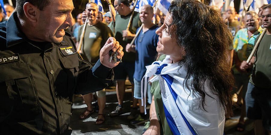 Eine Demonstrantin diskutiert vor einer Polizeistation mit einem Polizeibeamten während einer Demonstration gegen die Justizreform. Foto: Matan Golan/SOPA Images via ZUMA Press Wire/dpa