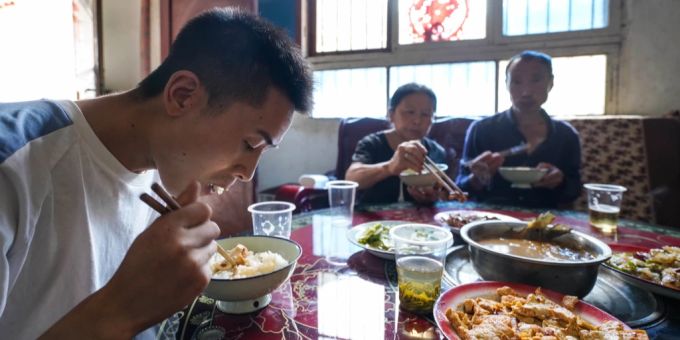 Ein junger Chinese in der Stadt Xiaogou sitzt gemeinsam mit seinen Eltern beim Abendessen. china arbeitslosigkeit