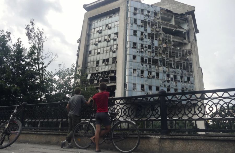 Zwei ukrainische Jungen sehen sich ein durch den Drohnenangriff zerstörtes Gebäude an.