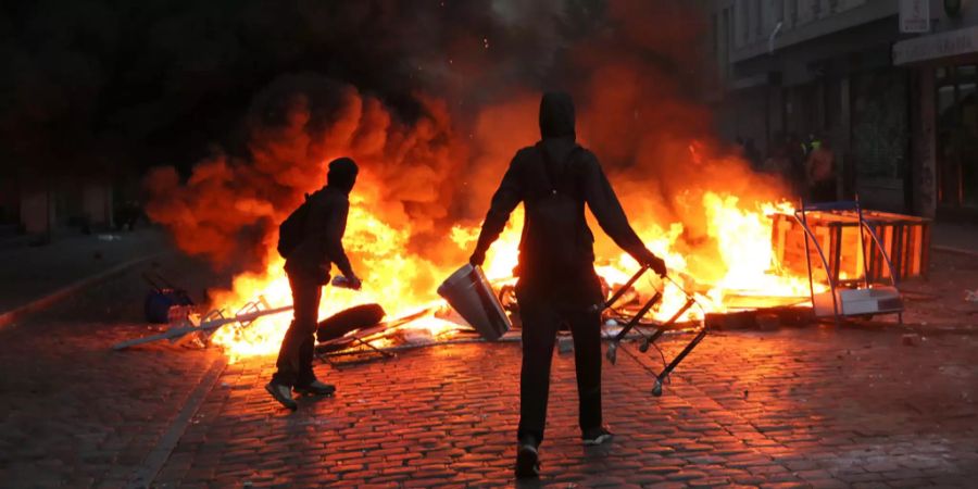 Randalierer stehen im Schanzenviertel bei den Ausschreitungen rund um den G20-Gipfel vor einer brennenden Barrikade.