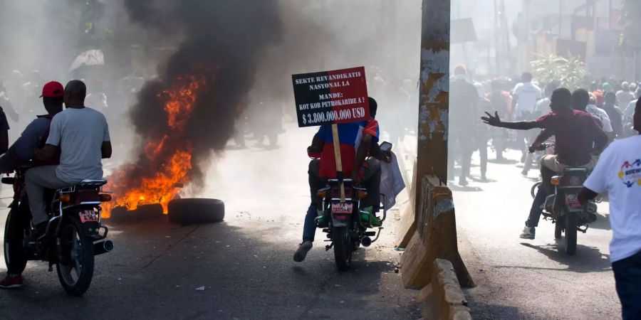 Demonstranten fahren während einer Demonstration gegen korrupte Politiker und mehr Transparenz an brennenden Reifen vorbei.