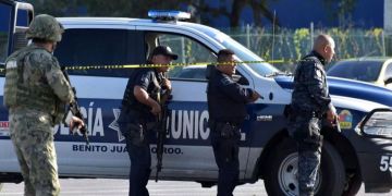 Polizisten stehen neben einem Polizeiwagen in Mexiko.