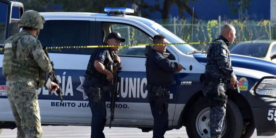 Polizisten stehen neben einem Polizeiwagen in Mexiko.