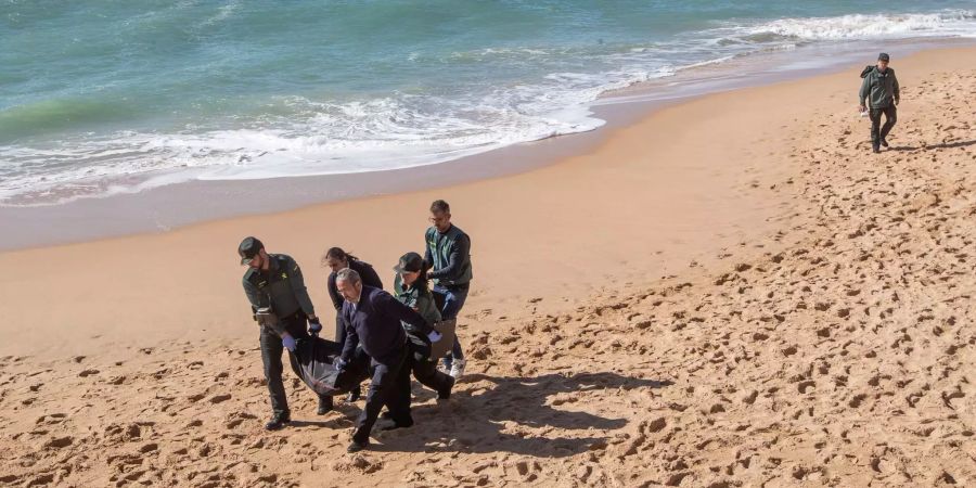 Spanische Behörden transportieren einen toten Flüchtling am Strand von Cadiz.