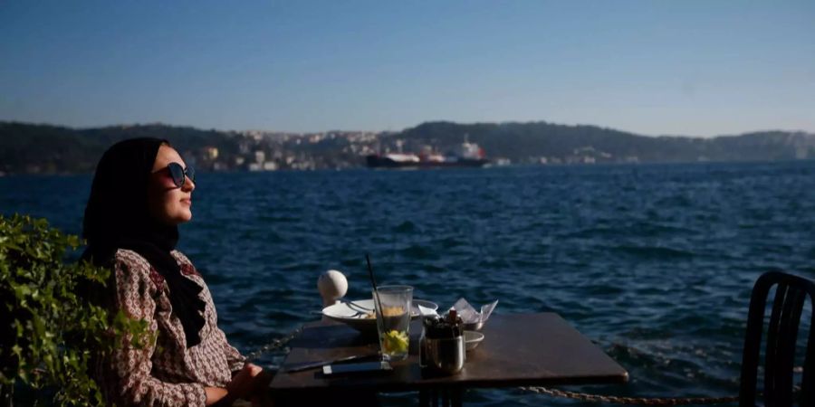 Eine Frau geniesst die Sonne am Bosporus in Istanbul.