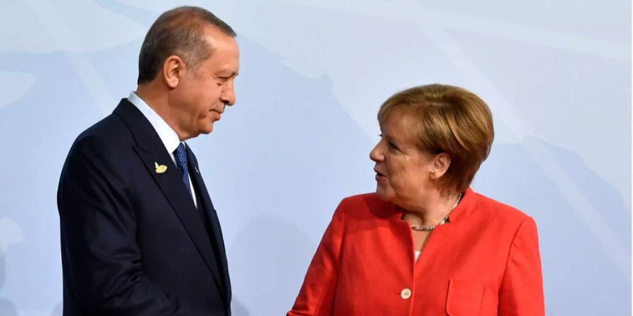 Der türkische Präsident Recep Tayyip Erdogan und die deutsche Bundeskanzlerin Angela Merkel schütteln sich die Hand und schauen sich in die Augen.