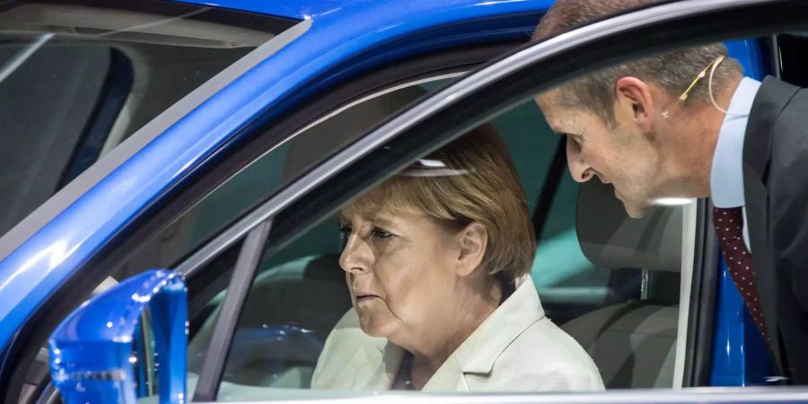 Bundeskanzlerin Angela Merkel sitzt nach der offiziellen Eröffnung der 66. IAA am Stand von Volkswagen am Steuer eines Hybridfahrzeuges vom Typ Tiguan GTE, den sie von VW-Markenvorstand Herbert Diess erklärt bekommt.