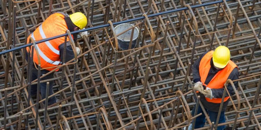 Bauarbeiter errichten ein Stahlgeflecht auf einer Baustelle.