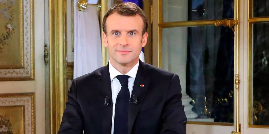 Der französische Präsident Emmanuel Macron lächelt vor seiner Fernsehansprache.