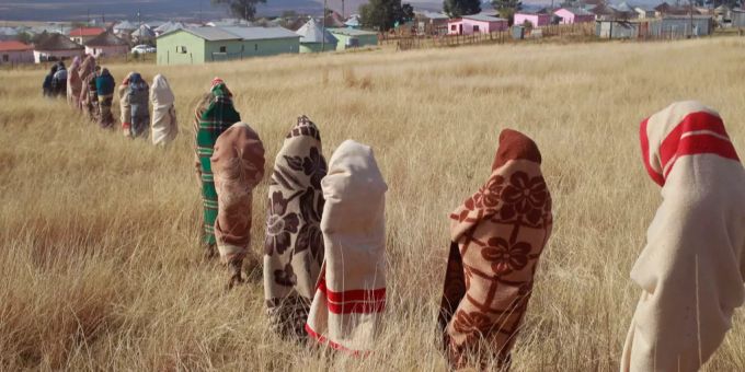 Junge Männer im Alter von 17 bis 20 Jahren von der Volksgruppe der Xhosa nahmen am Ritual teil, bei dem sie ohne Betäubung beschnitten werden. Junge Männer mit einer Denke um den Körper warten in einer Schlange auf einem Feld.