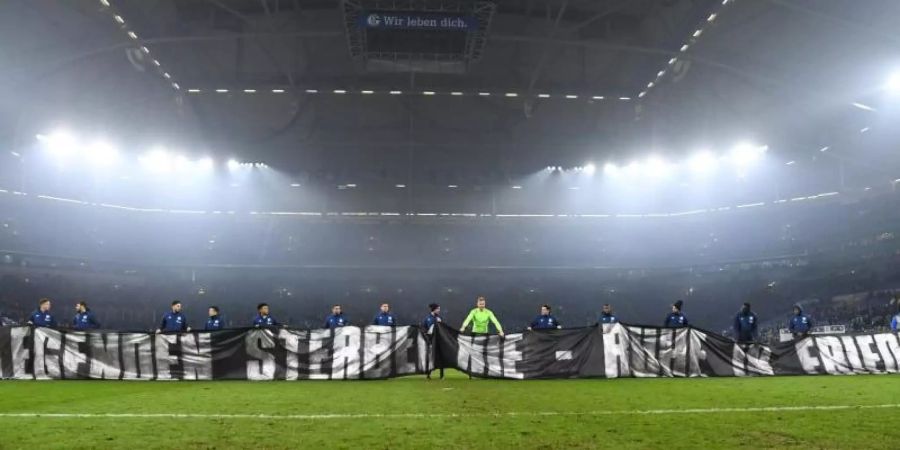 Die Schalker Spieler zeigten in Gedenken an den gestorbenen ehemaligen Schalke-Manager Rudi Assauer ein Fan-Spruchband. Foto: Ina Fassbender