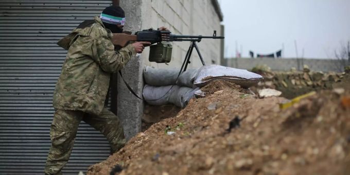 Ein von der Türkei unterstützter syrischer Milizionär zielt mit seiner Waffe. Ein Milizionär zielt mit seiner Waffe.