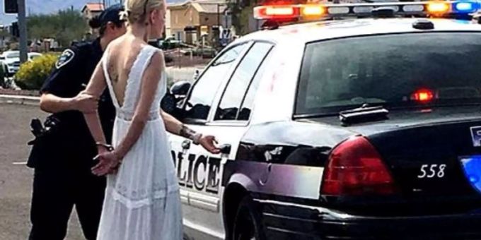 Ein nicht alltägliches Bild: Die junge Braut wird im Hochzeitskleid von einem Polizisten abgeführt. Ein nicht alltägliches Bild: Die junge Braut wird im Hochzeitskleid von einem Polizisten abgeführt.
