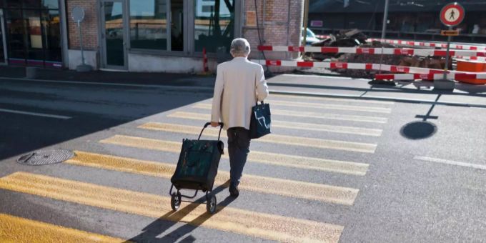 Eine ältere Frau überquert eine Strasse. frau