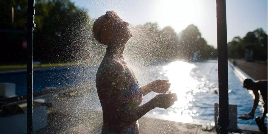 Eine Frau kühlt sich unter einer Dusche ab.