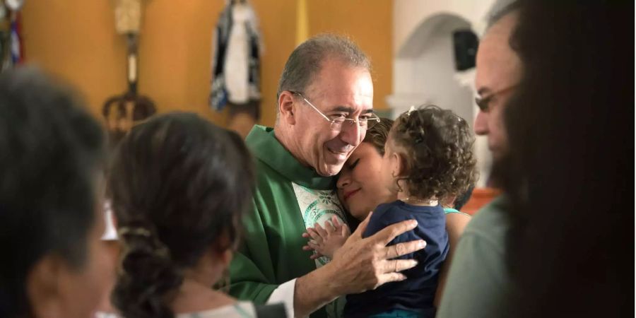 Pater Román wird in der Kirche San Miguel von Gemeindemitgliedern nach dem Gottesdienst umarmt.