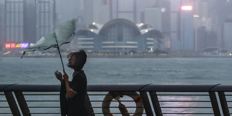 dpatopbilder - Der Regenschirm einer Frau wird weggeweht, als Taifun «Saola» mit starkem Wind und Regen auf Hongkong trifft. Foto: Daniel Ceng/AP/dpa