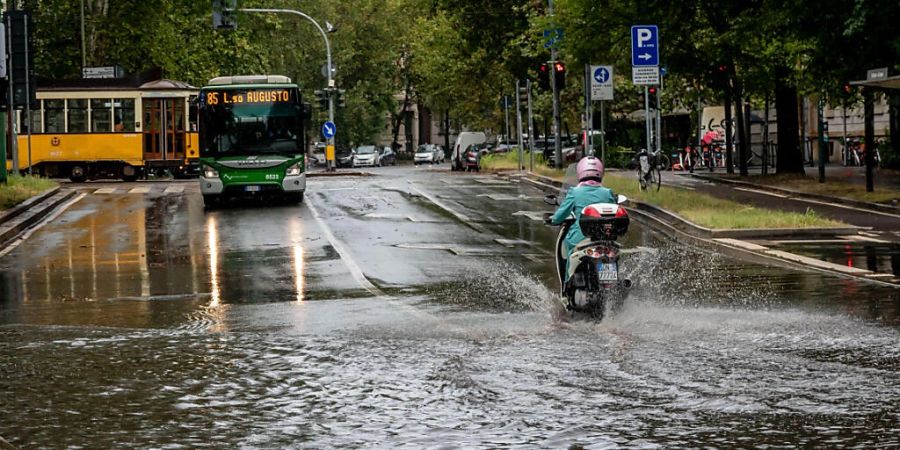 Eine Person fährt mit einem Motorroller eine überschwemmte Strasse entlang. Foto: Claudio Furlan/LaPresse via ZUMA Press/dpa
