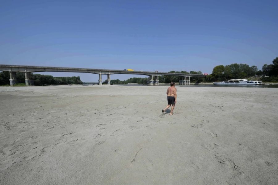 Ein Mann geht bei der Brücke bei Boretto durch das ausgetrocknete Flussbett des Po.