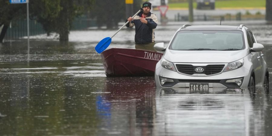 Ein Mann paddelt mit seinem Boot auf einer überfluteten Strasse am Stadtrand von Sydney.