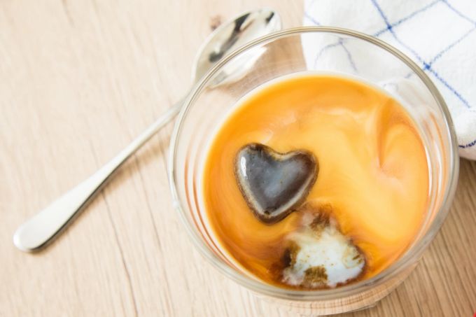 Kalte Erfrischung mit viel Koffein: Cold Brew Kaffee wird mit kaltem Wasser zubereitet und sollte mindestens vier Stunden ziehen. Glas Löffel Kaffee Schaum Herz Schoko