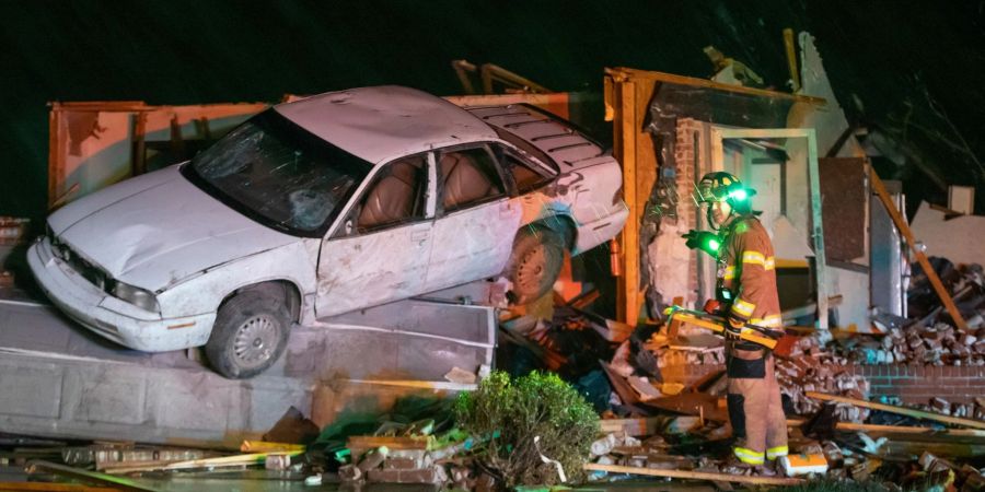 Ein Feuerwehrmann steht vor einem stark beschädigten Auto und Haus in Andover im Gebiet Kansas, nachdem ein Tornado durch das Gebiet östlich von Wichita gezogen ist.