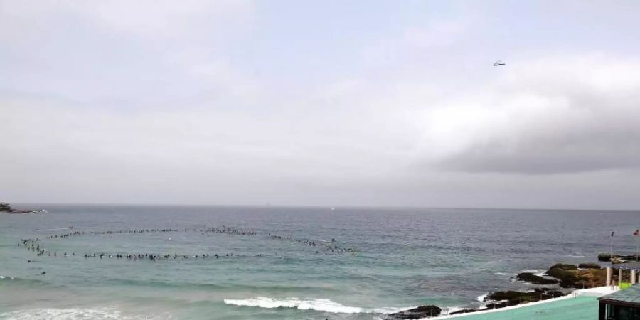 Surfer nehmen an einer Umweltaktion am Bondi Beach teil. In ganz Australien wurde gegen die Pläne des norwegischen Ölkonzerns Equinor protestiert, in den Gewässern vor der Grossen Australischen Bucht nach Öl zu bohren. Foto: Dan Himbrechts/AAP/dpa
