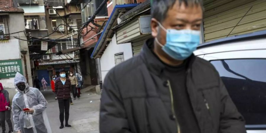 Menschen halten Abstand, während sie in Wuhan für Schweinefleisch anstehen. Foto: Uncredited/CHINATOPIX/dpa