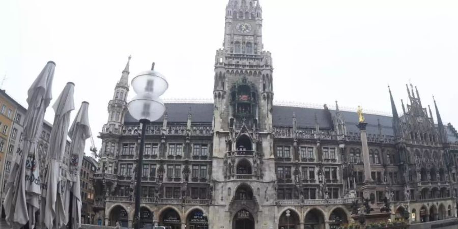 Vor dem Müncher Rathaus fährt ein Polizeiauto über den leeren Marienplatz. Foto: Felix Hörhager/dpa