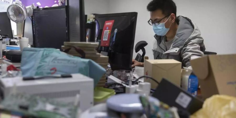 Ein Mann trägt bei der Arbeit in einem Technologieunternehmen in Peking einen Mundschutz. Foto: Mark Schiefelbein/AP/dpa